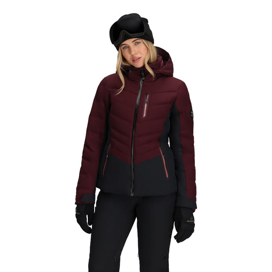Person wearing a maroon and black ski jacket with goggles on a white background