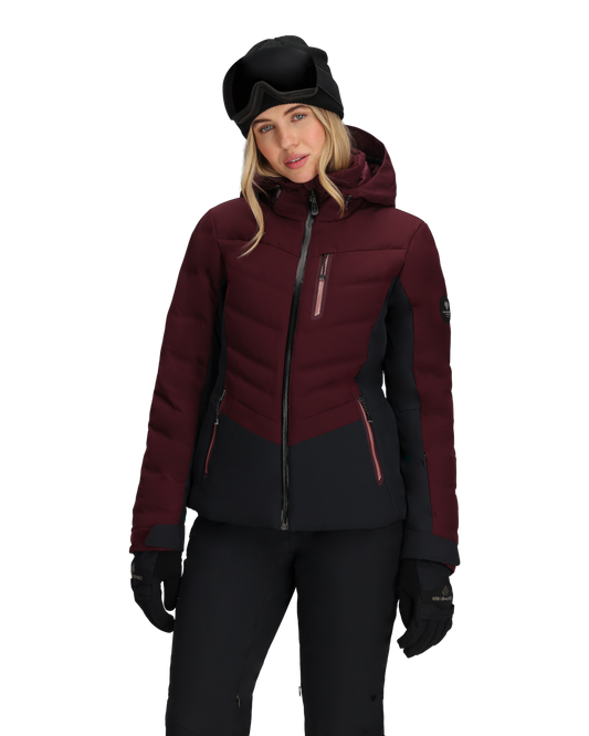 Person wearing a maroon and black ski jacket with goggles on a white background