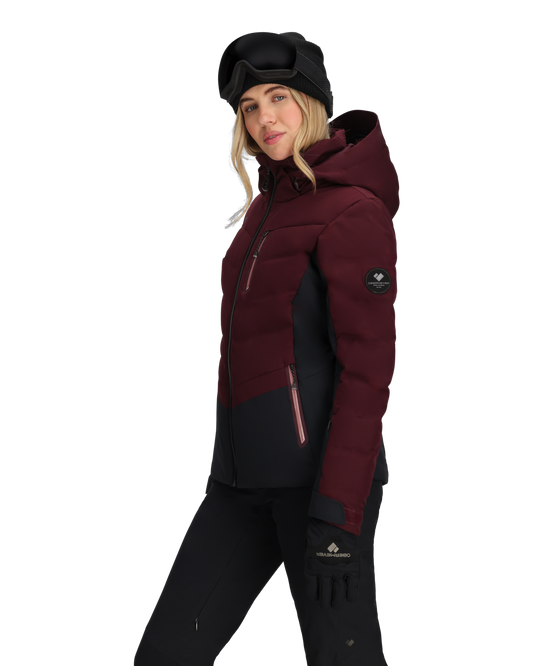 Person wearing a maroon and black winter jacket with a hood on a white background