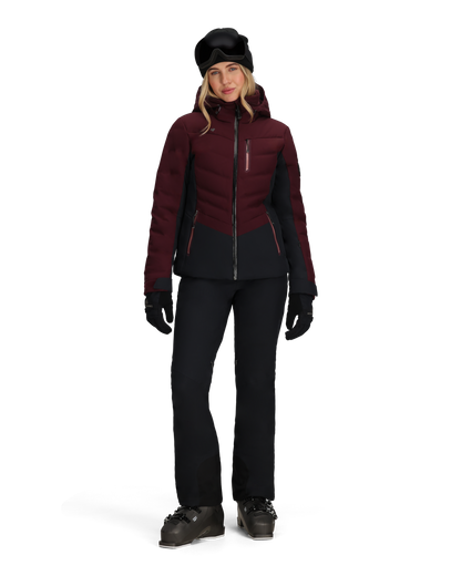 Person wearing a maroon and black winter jacket with black pants and gloves on a white background