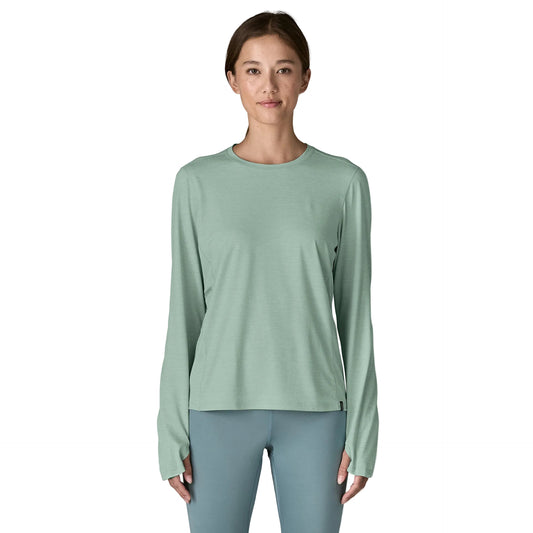 Woman wearing a light green long-sleeve shirt and gray leggings on a white background