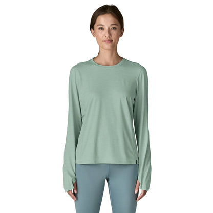 Woman wearing a light green long-sleeve shirt and gray leggings on a white background